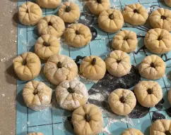 Step <p>Corte porciones de masa y forme bolitas de aprox. Ø 4 cm. Con un palillo o un objeto cortante, marque cada bolita haciendo una cruz + y luego otra cruz en forma de X. Coloque en el medio una pipa de calabaza.</p> illustration